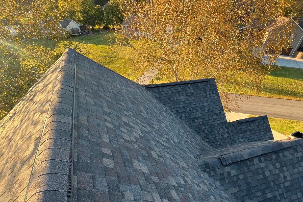 Ridge vent running along the peak of an architectural shingle roof, lit by low autumn sun
